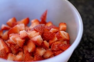Chopped strawberries mixed with sugar in a white bowl