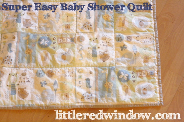 Super Easy baby shower quilt with light blue, light green and baby animal pattern on a wood floor
