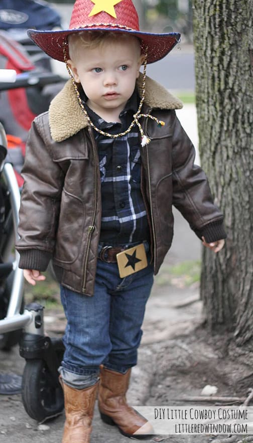 toddler wearing a cowboy costume next to a tree