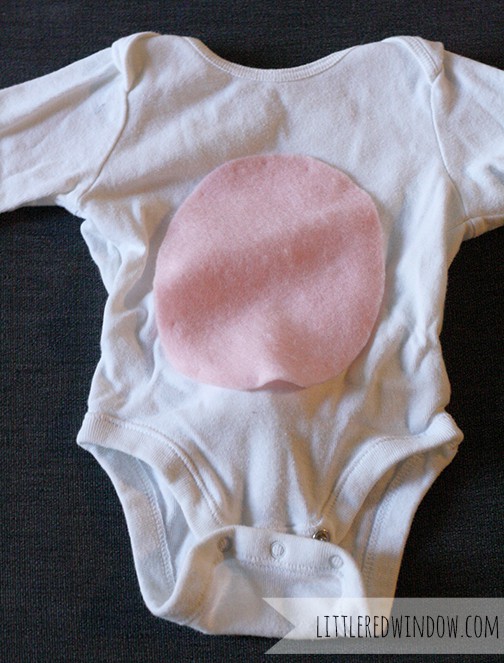 white onesie with pink felt oval on the tummy