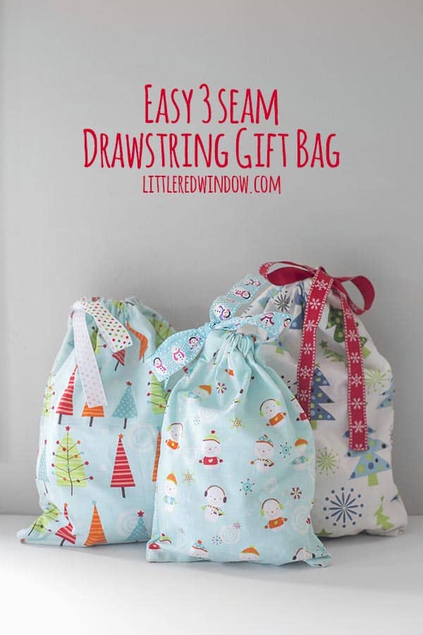 three fabric gift bags with trees and snowmen on them and tied with ribbon on a white surface