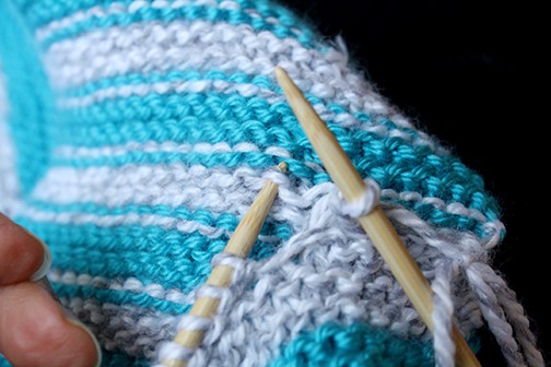 Photo showing how to use left needle to pick up a stitch from the body of the scarf