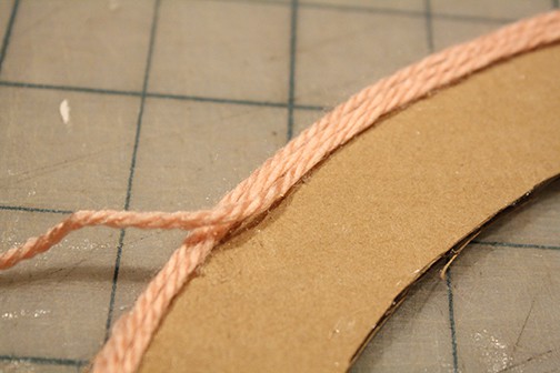 Continue covering the cardboard wreath circle with pink yarn