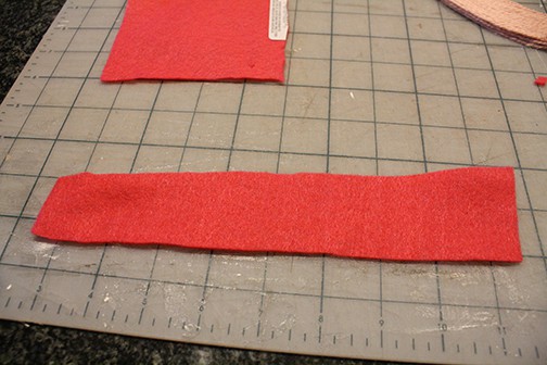 A 2 inch wide strip of hot pink felt on a gray cutting mat