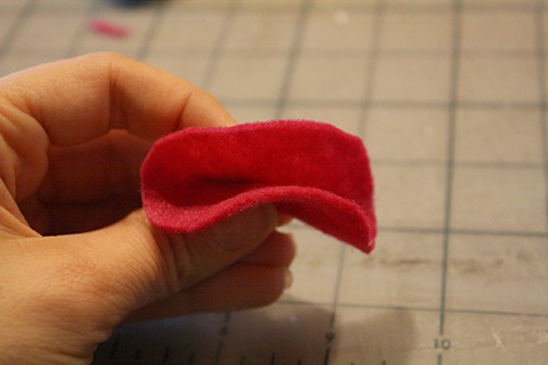 hand pinching the small felt circle in half at the middle