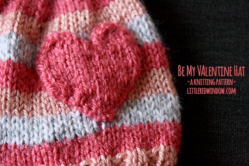 closeup of  pink striped hat with a heart on a dark background
