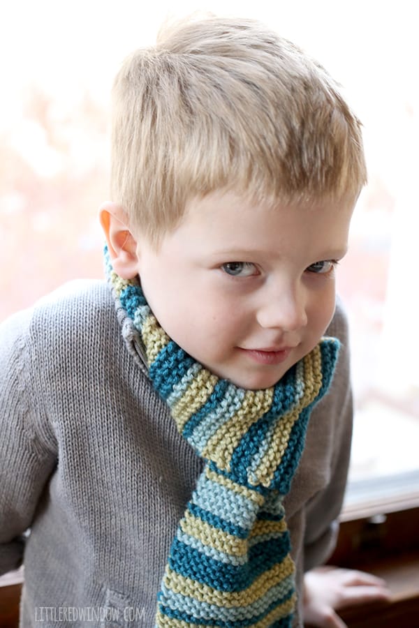 Smiling boy wearing gray sweater and green and blue striped scarf
