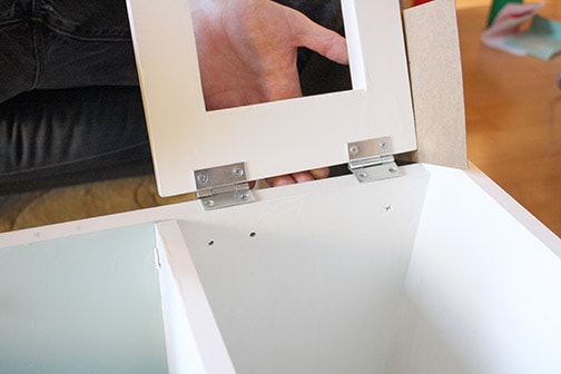 a hand holding the microwave door as the hinges are attached