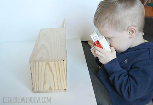 little boy taking a picture of wood box with toy camera