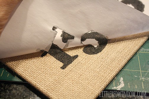 Stencil being peeled off burlap canvas