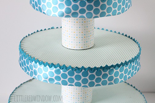 Closeup of Cupcake stand with three tiers and teal polka dot ribbon around the edges