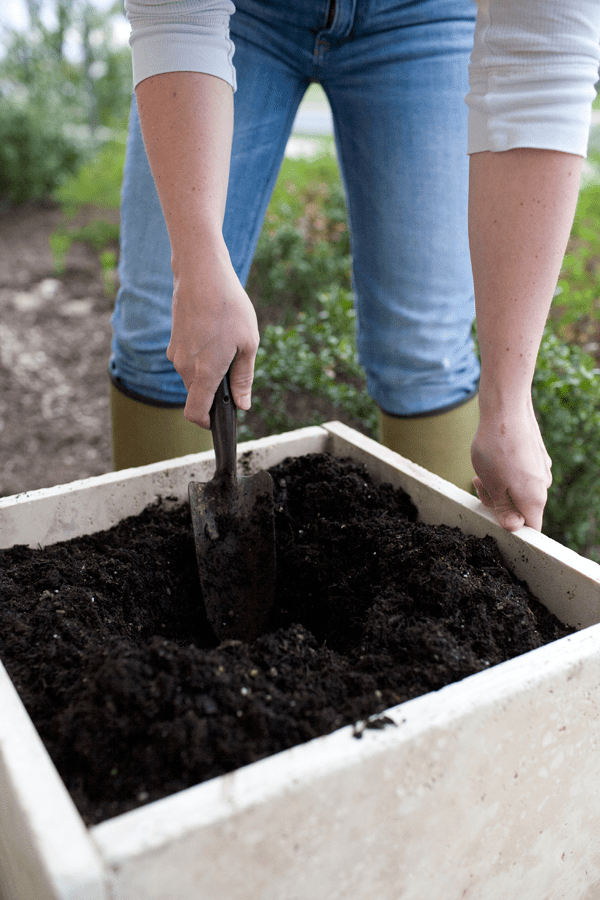 Person digging in a square planter with a shovel