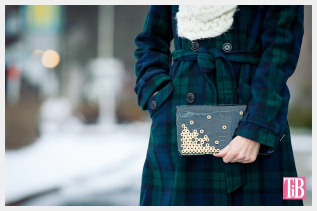 Person holding a clutch purse decorated with hardware nuts