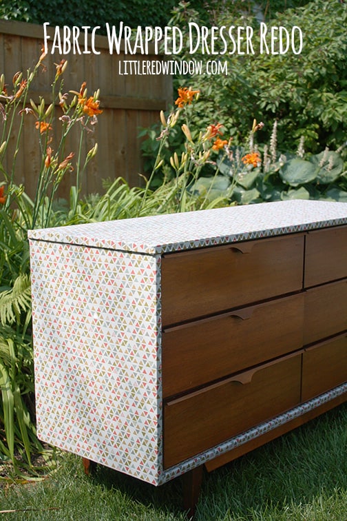 Finished fabric wrapped dresser outside in front of a garden