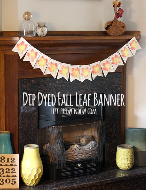 Finished banner with fanric pennants and wood leaves on top hanging across a fireplace mantel