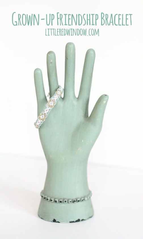 Sea green hand shape with a friendship bracelet draped over the fingers