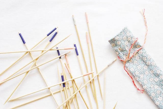 long bamboo sticks with strips of color at one end and fabric pouch to hold them