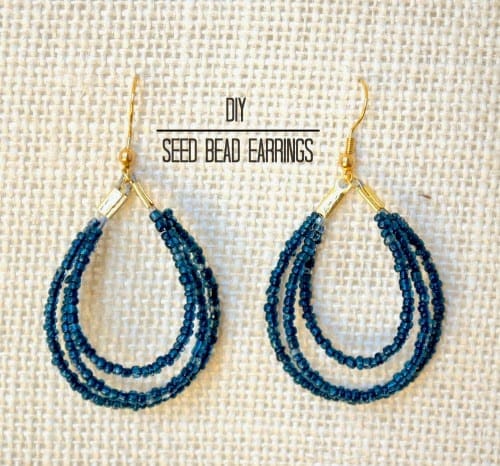 A pair of gold earrings with dangling hoops made from loops of dark blue seed beads