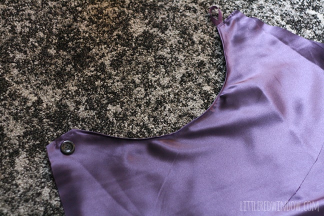 purple satin cape with buttons being applied