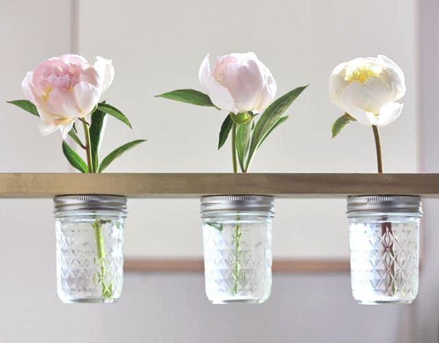 wood shelf with glass jars fastened underneath holding flowers