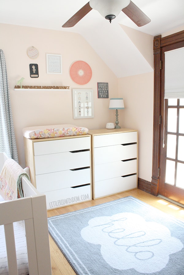 pink nursery with two white dressers and a gallery wall