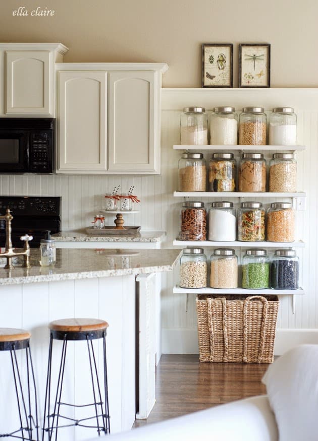 white wall shelves with glass jars on them in a kitchen