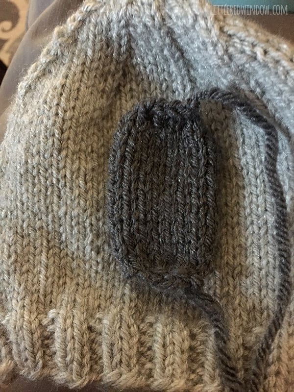 gray knit hat with dark gray knit koala nose placed on top 
