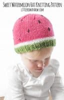 Chubby baby wearing knit hat with green brim and pink top to look like a watermelon and looking down and to the right