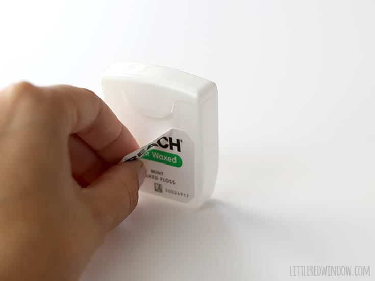 hand peeling off the label from a whitedental floss container