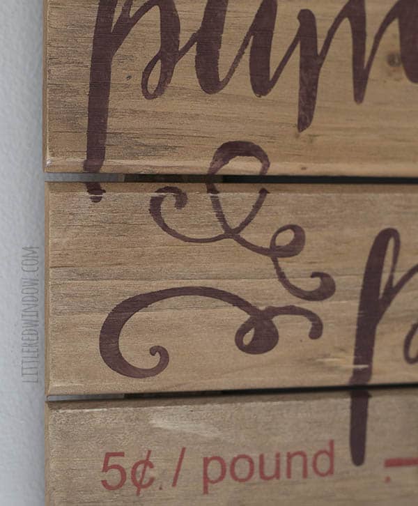 closeup of stenciled design on slatted wood pumpkin patch sign showing swirly accent in brown paint