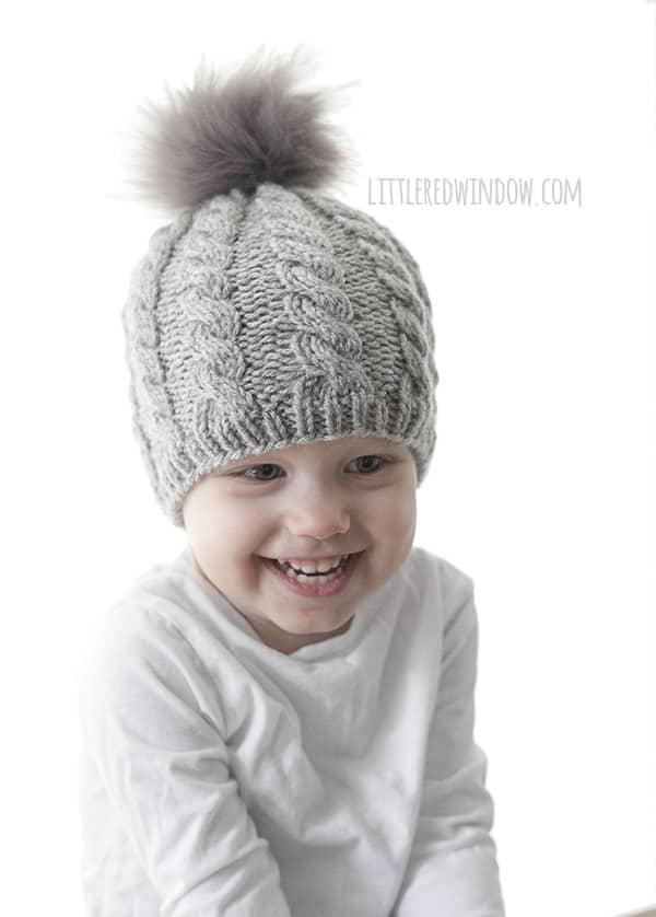 Twist Cable Hat Pattern for newborns, babies and toddlers! This cute cable pattern and faux fur pom pom will look adorable on your little one this winter, time to start knitting! | littleredwindow.com