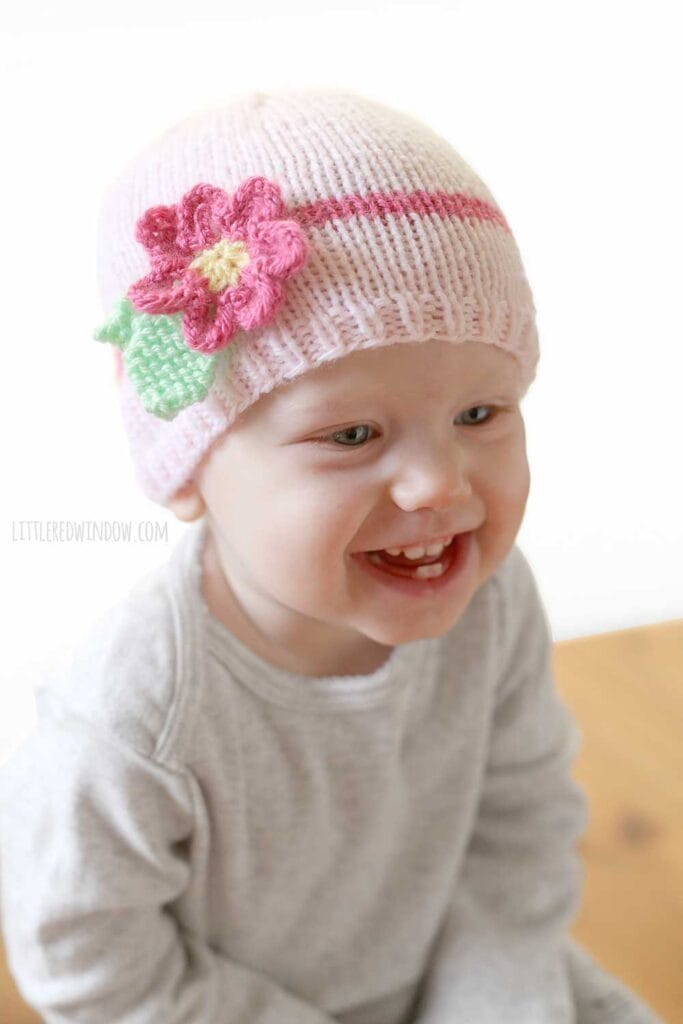laughing baby wearing light pink knit spring daisy flower hat with dark pink band and knit flower