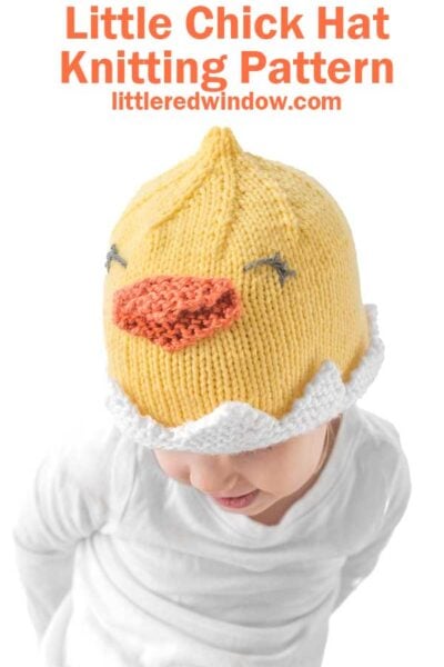 A child in a white shirt sports an adorable chick hat—a yellow knitted creation with an orange beak and closed eyes. The text reads "Little Chick Hat Knitting Pattern" and "littleredwindow.com.