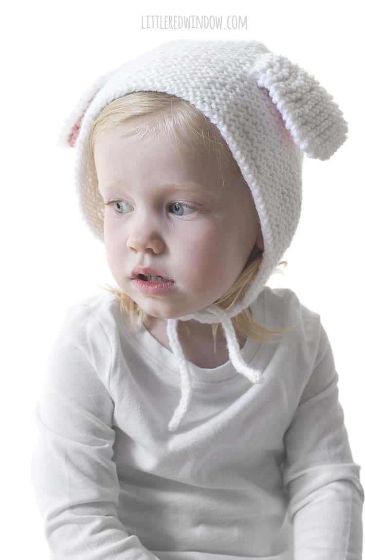 Smiling little girl wearing a white bonnet with lamb ears