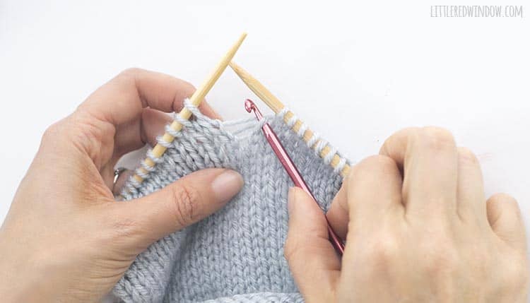 Insert a crochet hook through the dropped knit stitch