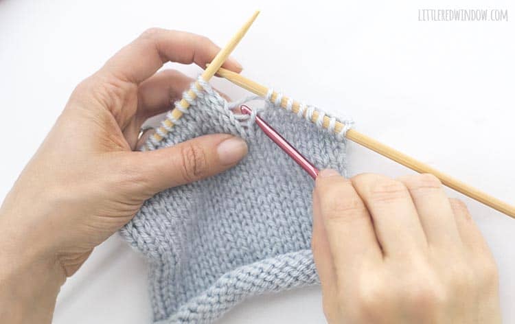 Grab the horizontal yarn behind the dropped knit stitch with your crochet hook