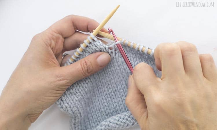Insert a crochet hook through the dropped knit stitch