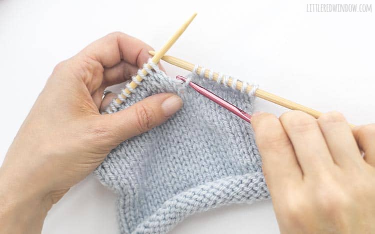 Grab the horizontal yarn behind the dropped knit stitch with your crochet hook