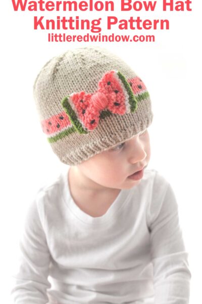 A child wearing a knitted bow hat with a watermelon design sits facing slightly to the left. The hat is beige with pink, green, and black watermelon slice details. Text above the child reads "Watermelon Bow Hat Knitting Pattern littleredwindow.com".