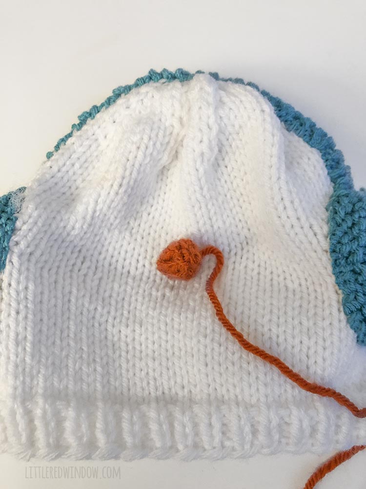 Use the cast on tail to sew the carrot nose to the front of your snowman hat