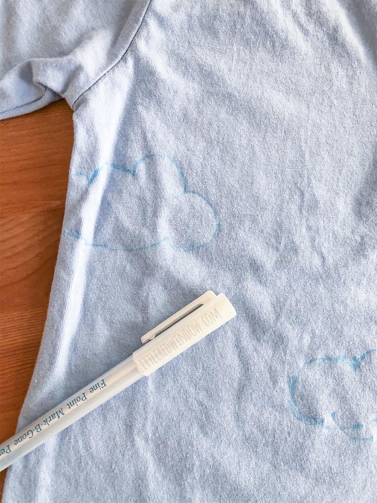 To make the sky for a DIY butterfly garden costume, first sketch the clouds and sun on a blue tshirt with a disappearing ink pen!