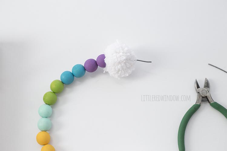 Add a pom pom to the end of your DIY rainbow wall hanging!