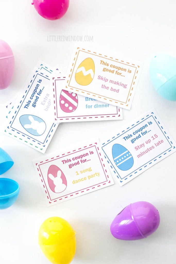 Pastel colored coupons on a white table next to colored plastic easter eggs