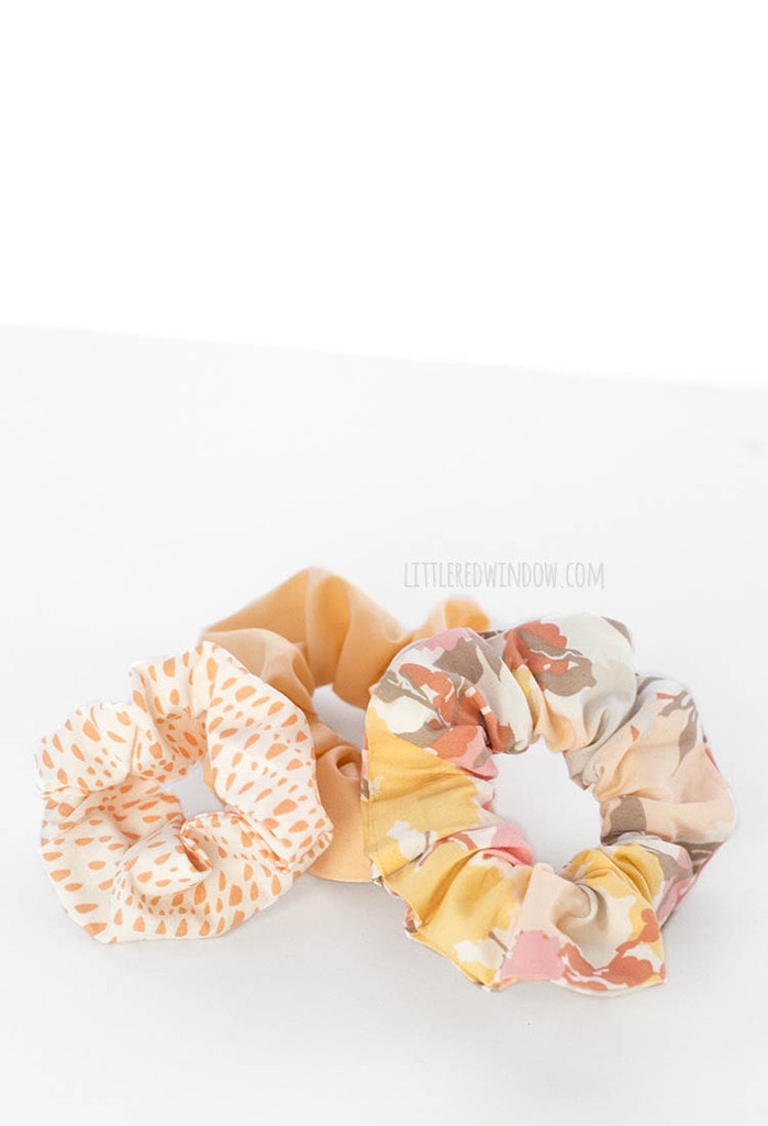 Three no sew scrunchies in peach floral and orange dot cotton prints arranged together on a plain white background