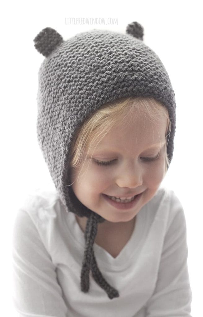 Smiling little girl wearing a gray knit bonnet with bear ears