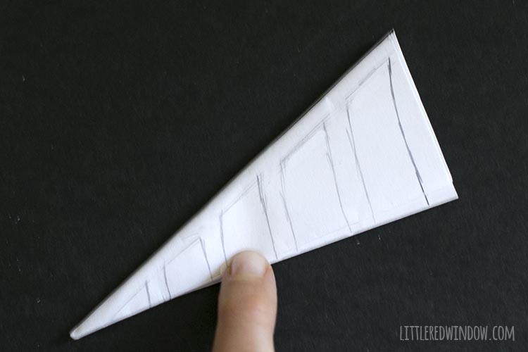 folded triangle of paper with pencil sketch of spiderweb shape on it