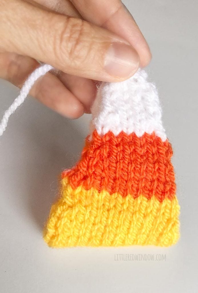 hand holding candy corn knitting folded in half along the yellow middle