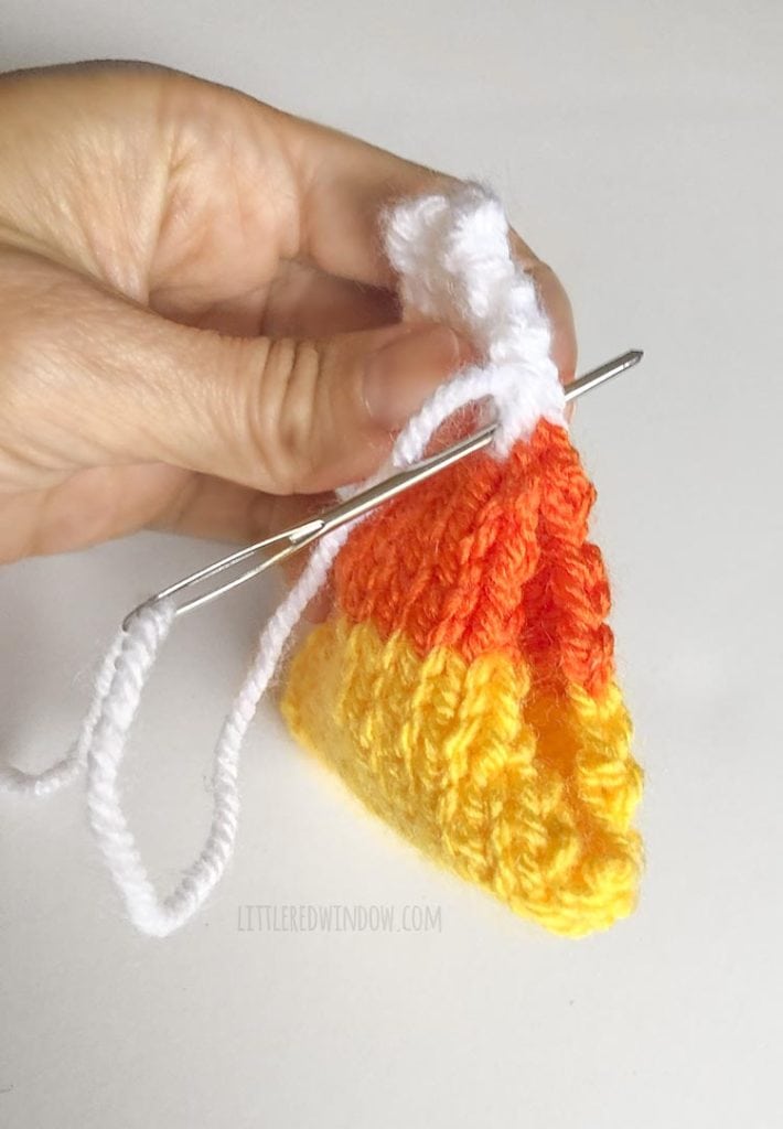 hand sewing one side of a knit candy corn shape together