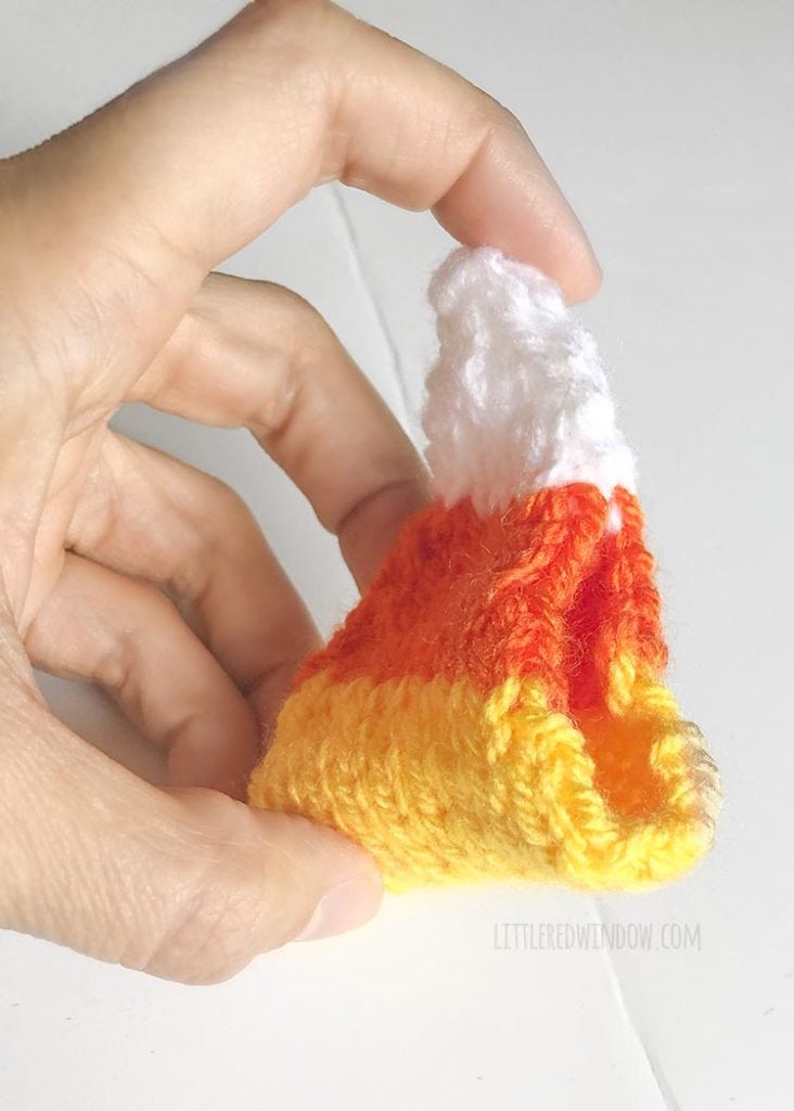 hand holding knit candy corn shape with part of one side still open to stuff