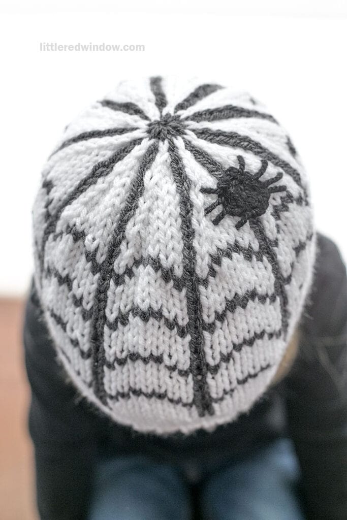 Knitted hat with spiderweb and spider design for Halloween.